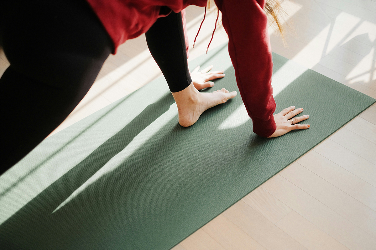 Woman with red jumper in yoga position using a green yoga mat- Photo by Junseong Lee- Kai Interiors Hackney