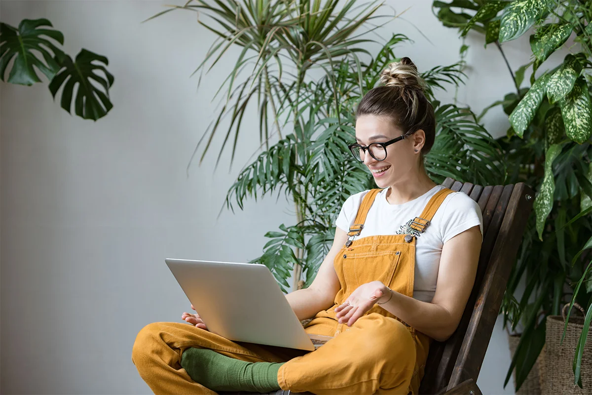 An image of a woman working from home on videocall with plants in the background Hackney Kai Interiors